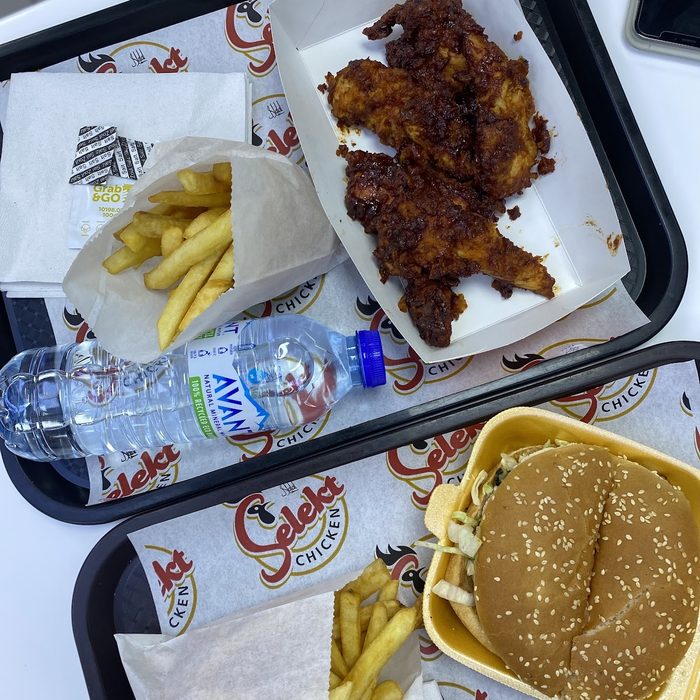 A full meal tray of fried chicken, chips, a burger and a drink